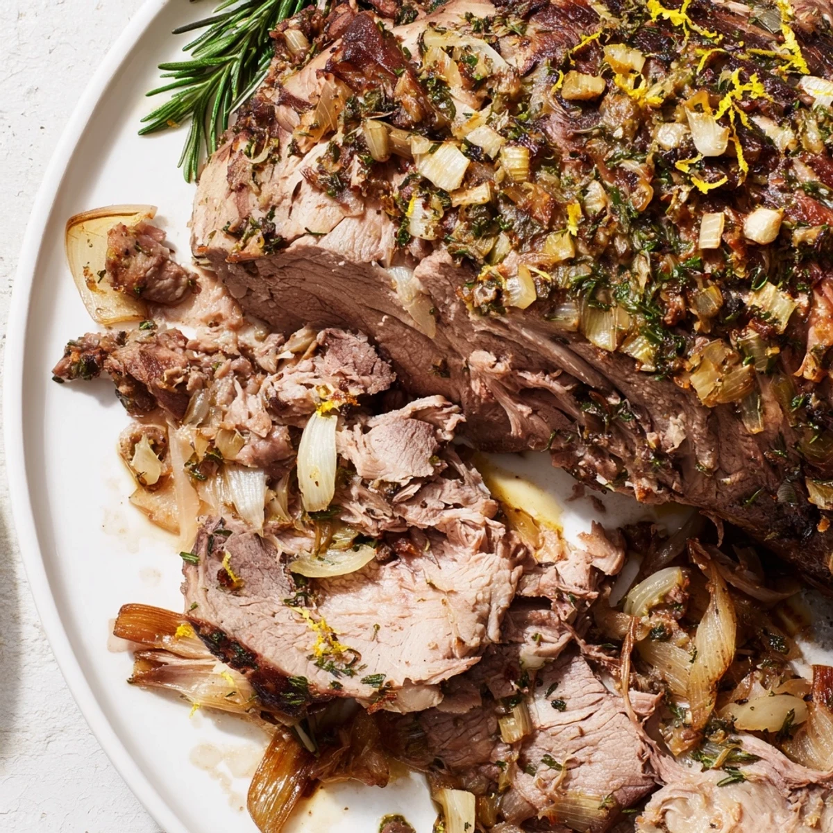 This beautiful Roasted Lamb, cooked to perfection, is presented with roasted vegetables and fresh rosemary sprigs.