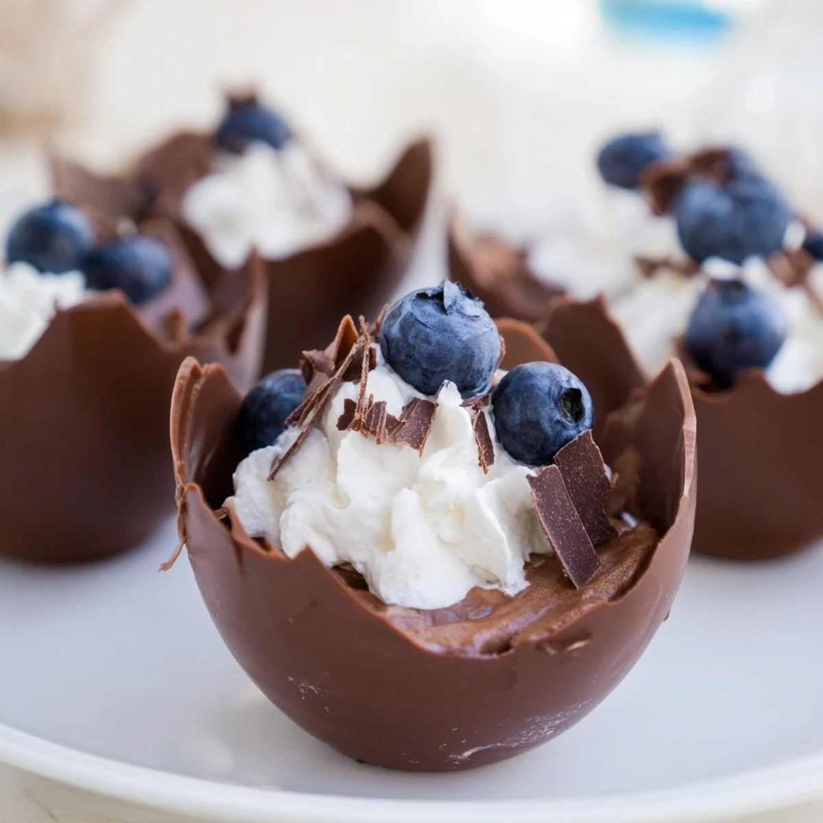 Silky chocolate mousse filling edible, dark chocolate cups; a sophisticated dessert recipe idea.