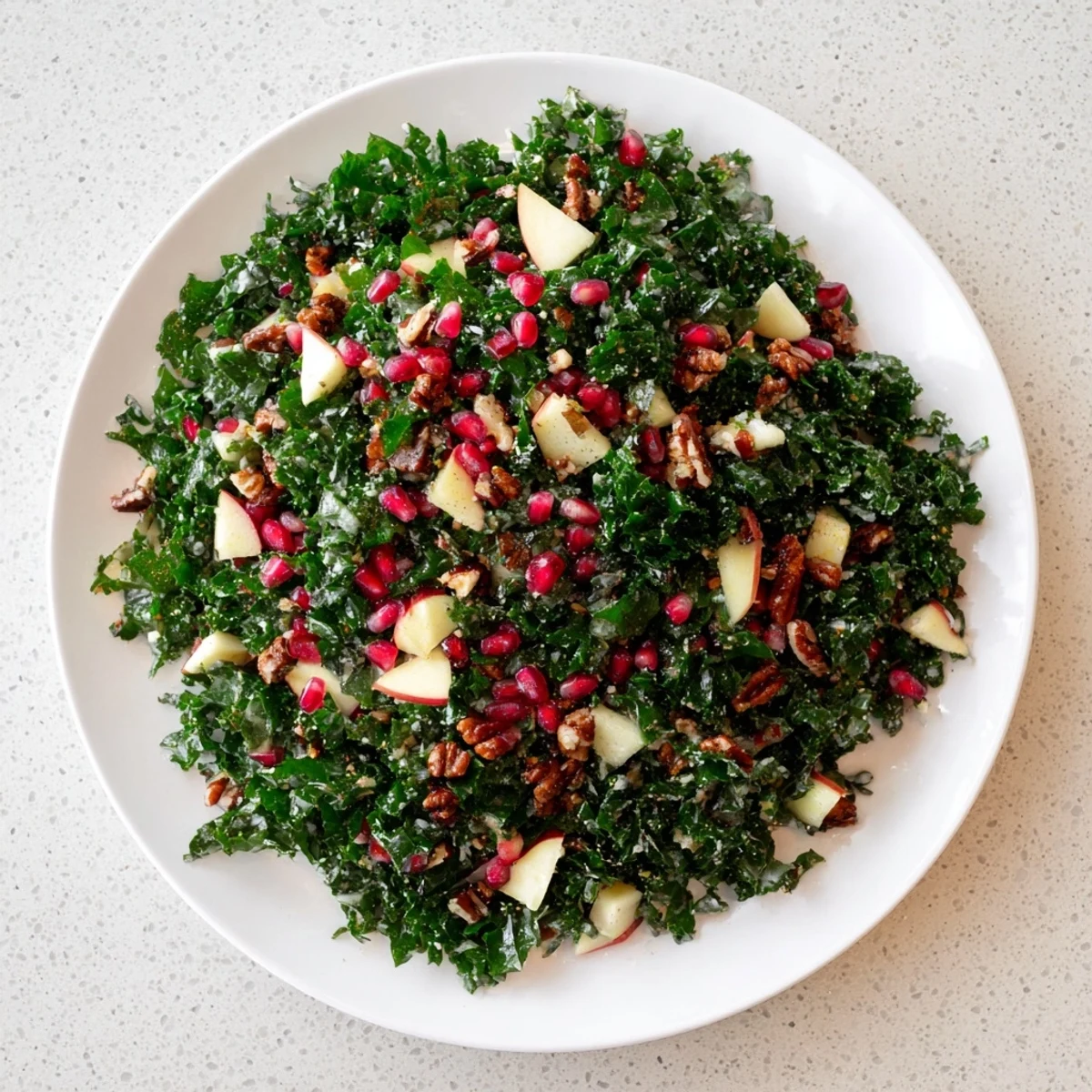 A bright bowl of Winter Kale Salad with Pomegranate, showing tender kale and a tangy dressing glistening.