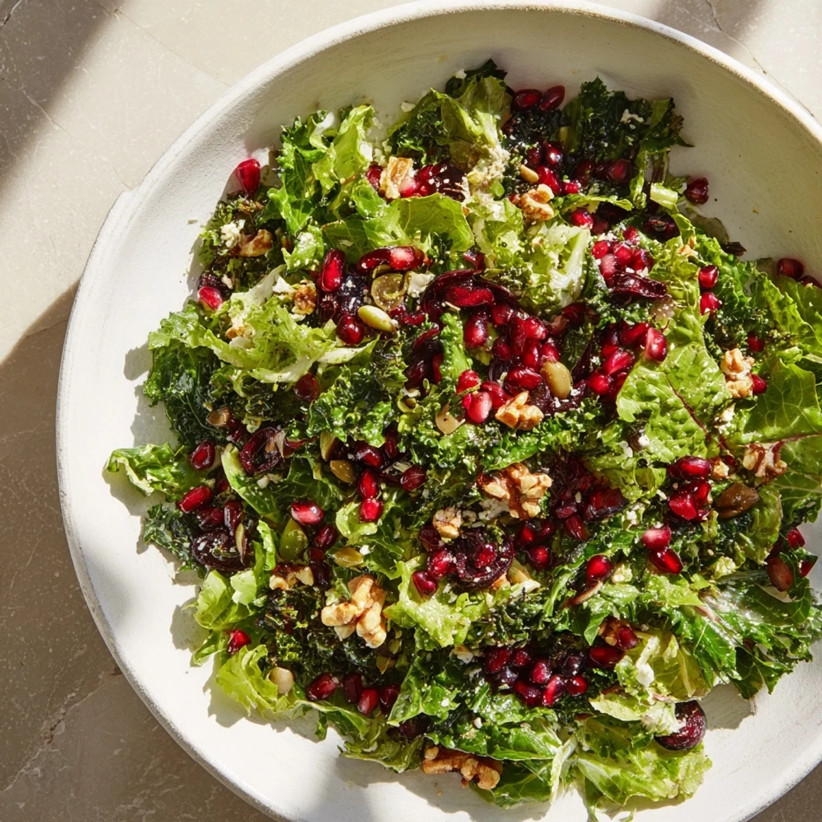 Brightly colored Winter Greens with Pomegranate Vinaigrette in a glass bowl, ready to serve and enjoy.