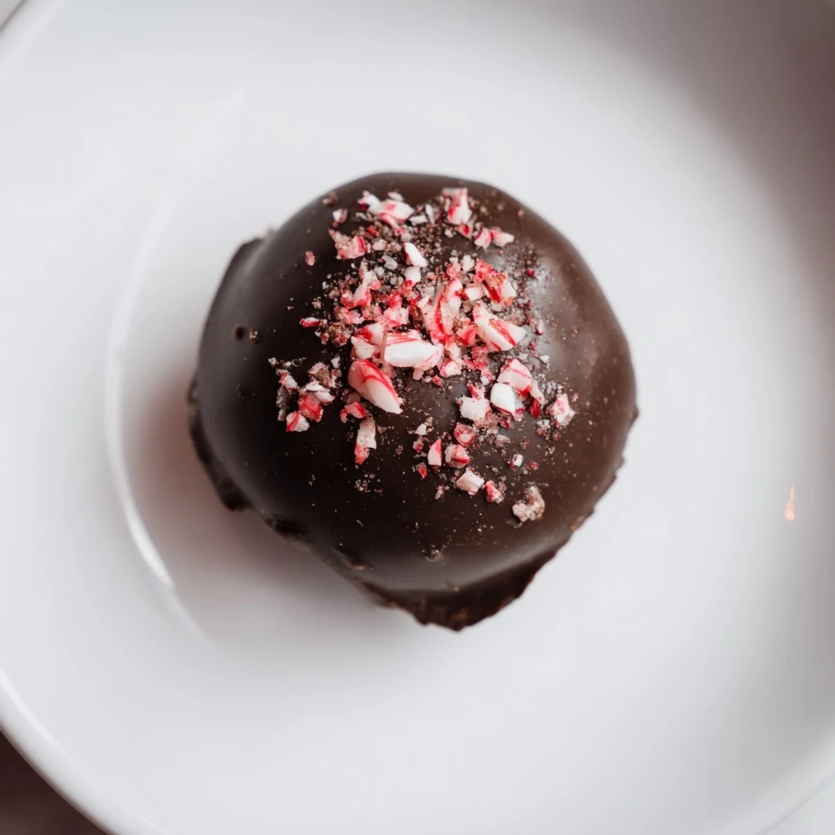 A close-up of glossy Peppermint Mocha Truffles, with crushed peppermint scattered around them.