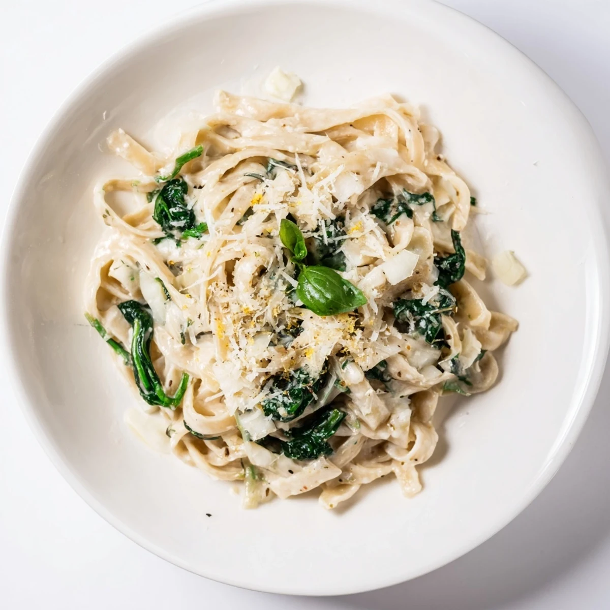 Fresh spinach pasta tossed in garlic cream sauce, garnished with basil for a vibrant vegetarian meal.