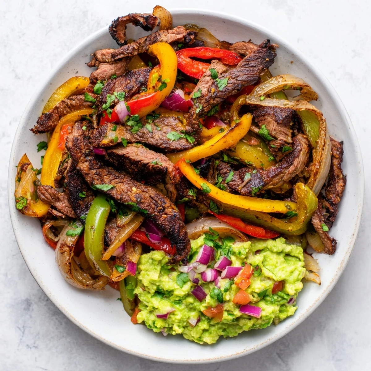 A close-up of flavorful beef fajitas, complete with fresh guacamole and warm tortillas, ready to eat.