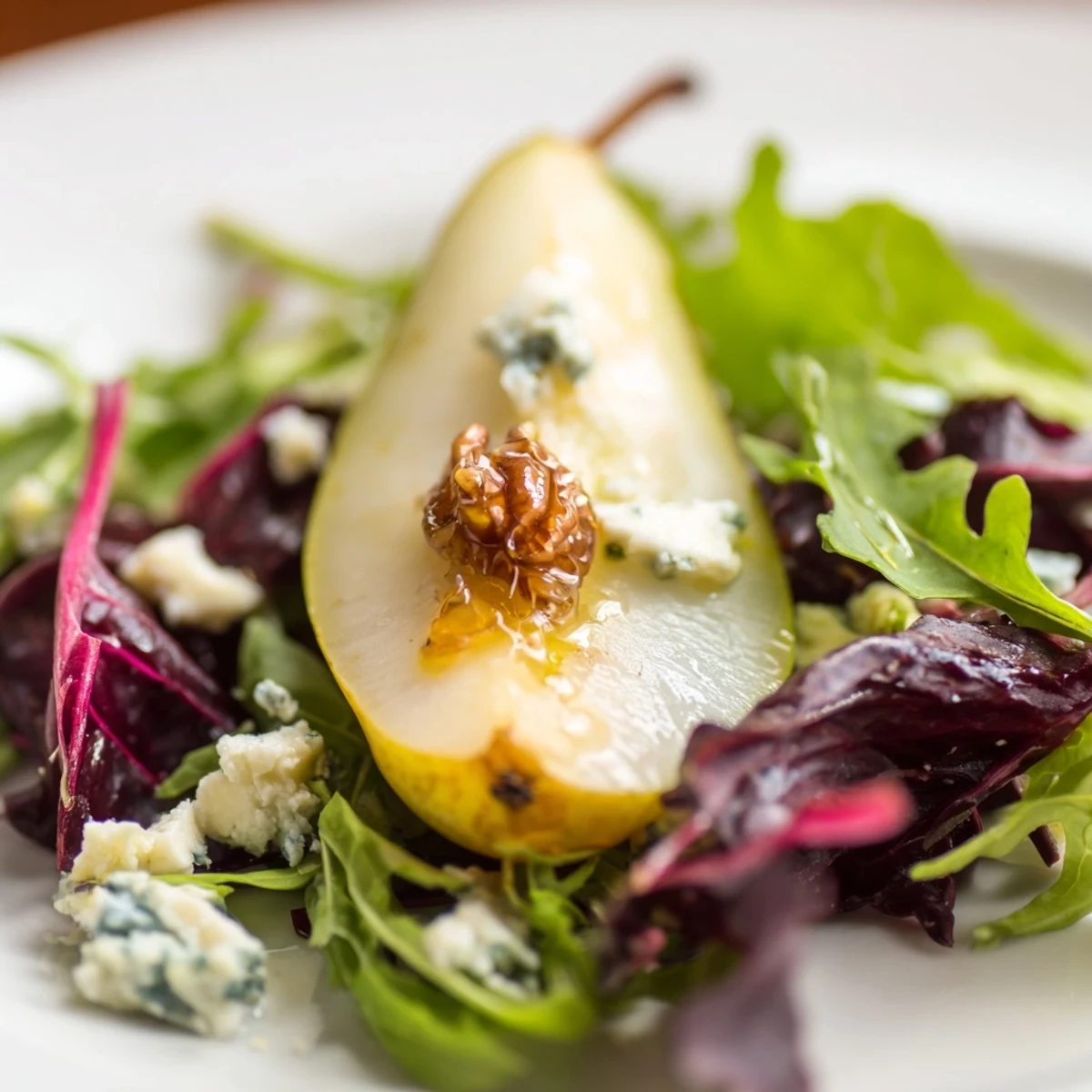 Freshly sliced pears and blue cheese top crisp winter greens, garnished with glossy candied walnuts and red onion in this Winter Green Salad with Pear and Candied Walnuts.