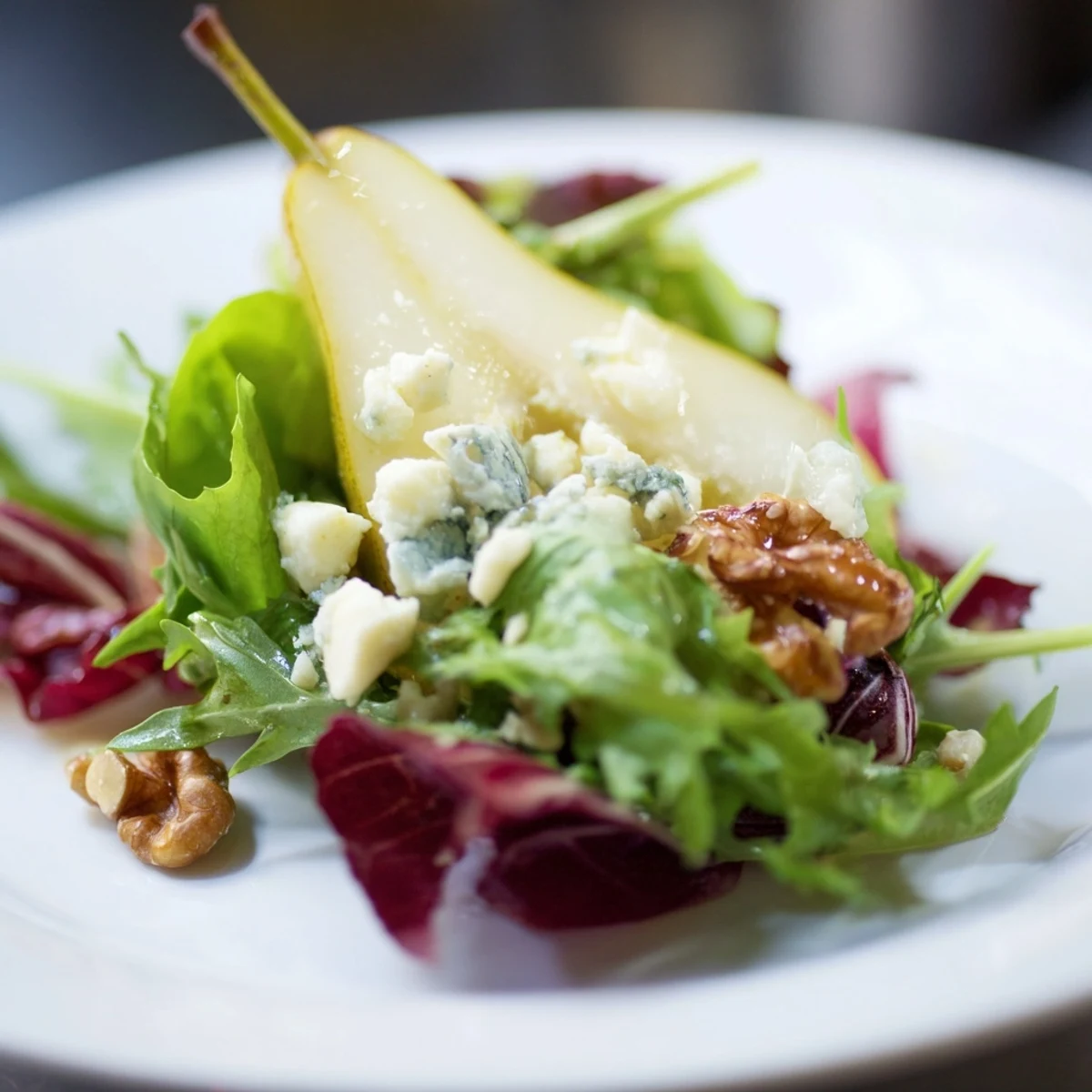 Dressed in tangy apple cider vinaigrette, the Winter Green Salad with Pear and Candied Walnuts features juicy pear slices and crumbled cheese on deep green leaves.