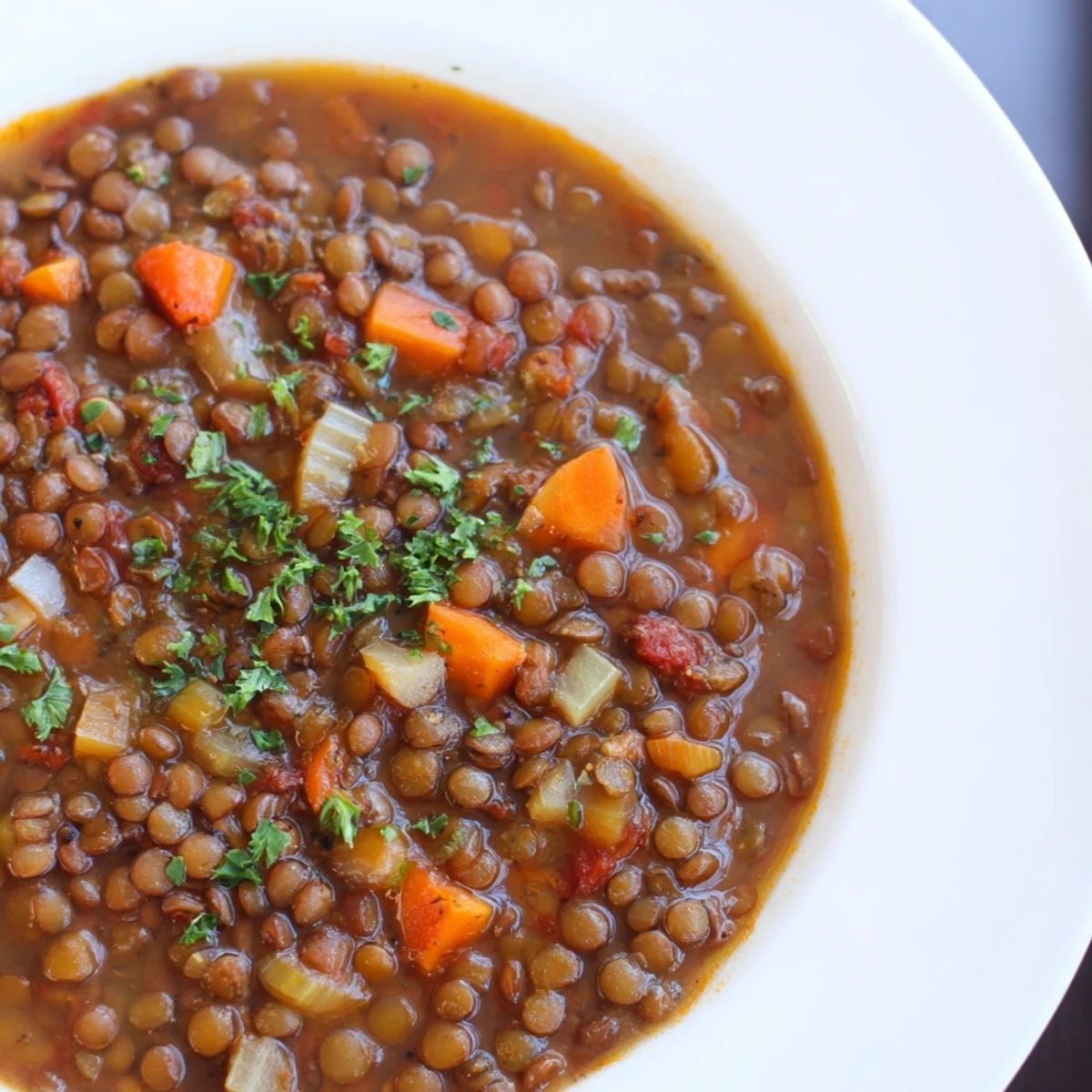 A rustic mug of Spicy Lentil Soup with Carrots and Celery paired with crusty bread on the side.