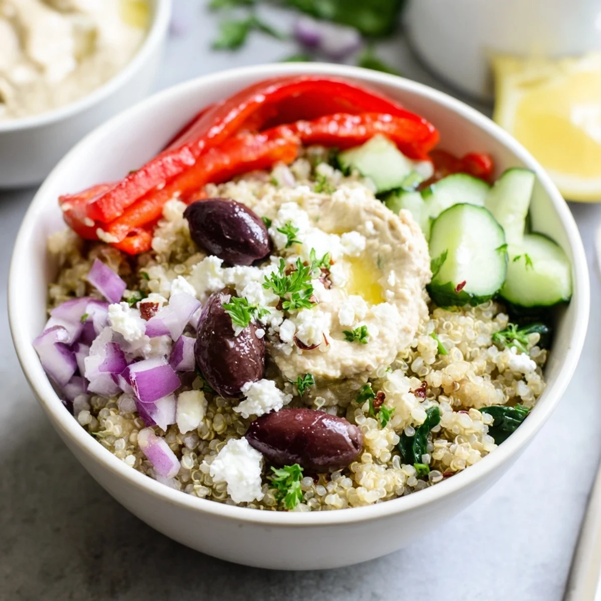 A served Mediterranean Quinoa Bowl drizzled with olive oil, garnished with parsley, and enjoyed with hummus for a nourishing meal.