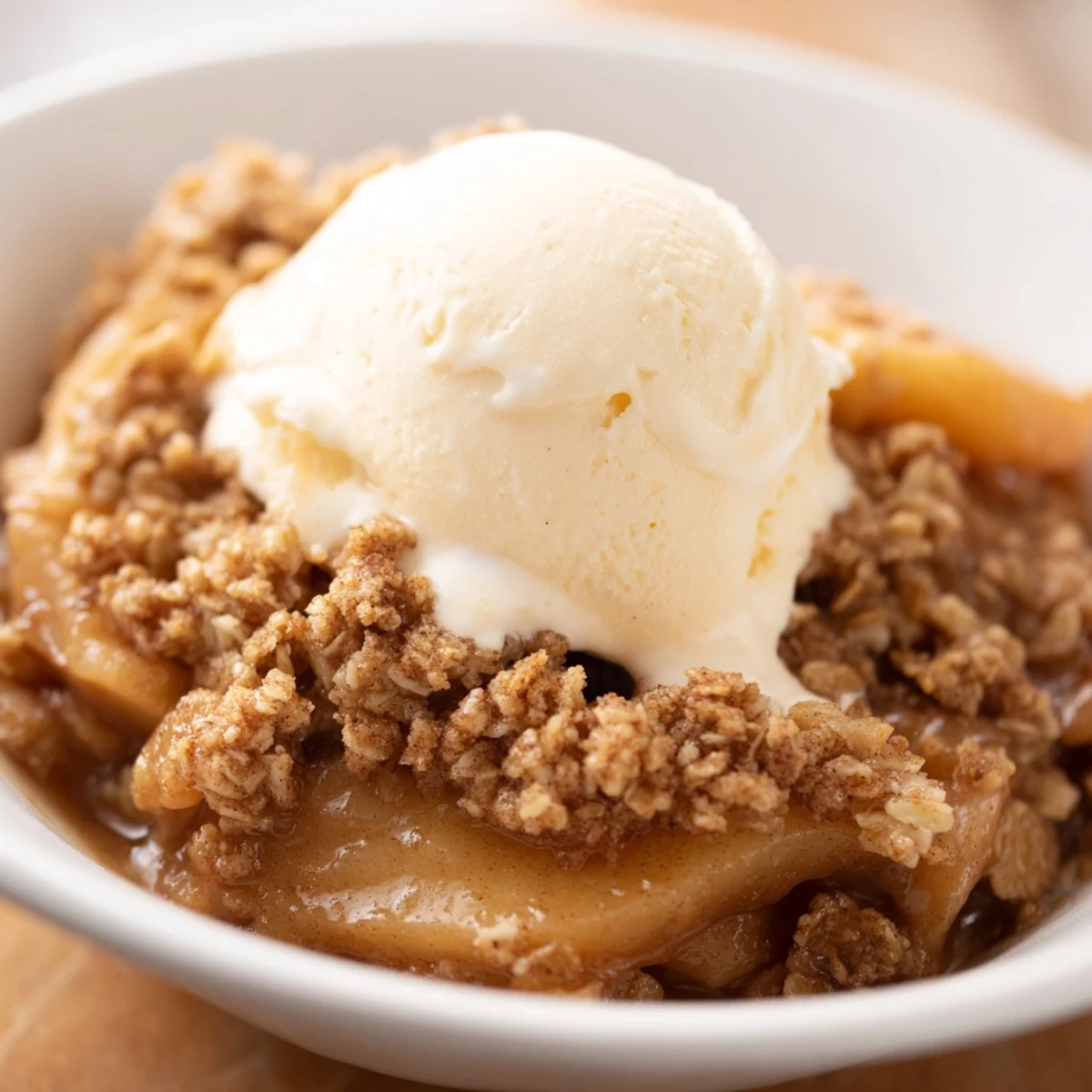Serve warm Baked Apple Crisp with a scoop of vanilla ice cream melting into the sweet fruit.