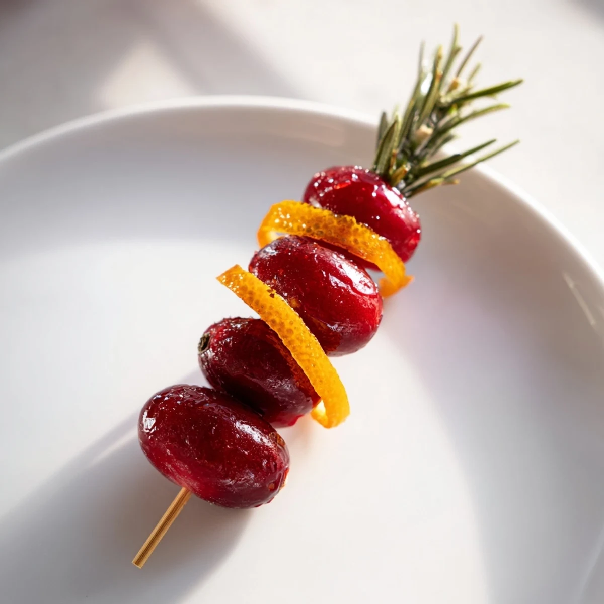 Cranberry and citrus skewers with rosemary sprigs for cocktail presentation.
