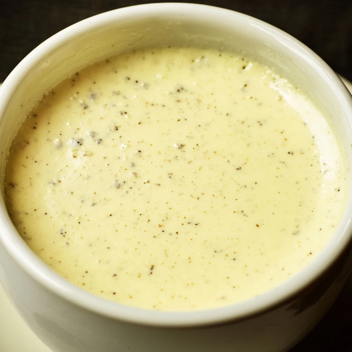 Four elegant ramekins of Creamy Custard with Vanilla chilling on a cooling rack, ready to be served after a dinner party.