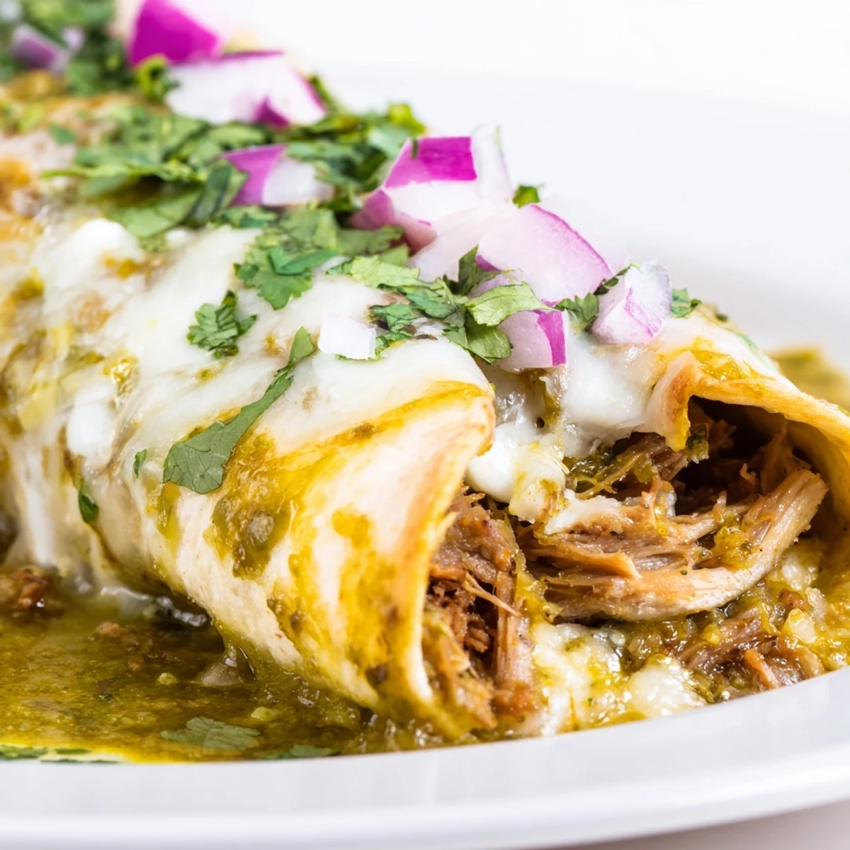Beef Enchiladas with Green Chili Sauce baked to a golden bubbly finish, topped with fresh cilantro and red onion on a rustic plate.