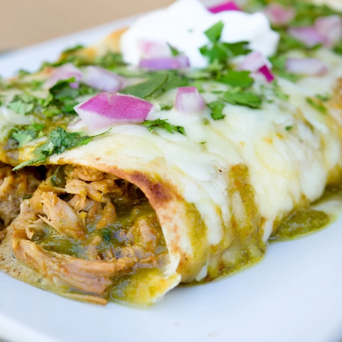Fork-tender shredded beef rolled in flour tortillas, smothered in creamy Beef Enchiladas with Green Chili Sauce, served with lime wedges.
