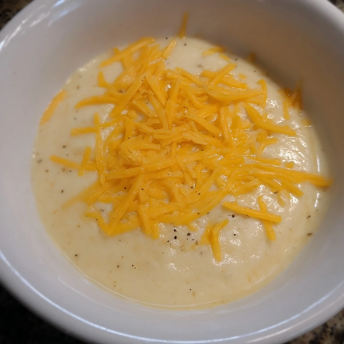 Freshly made Southern Cheesy Grits served in a rustic bowl, garnished with a pat of melting butter.