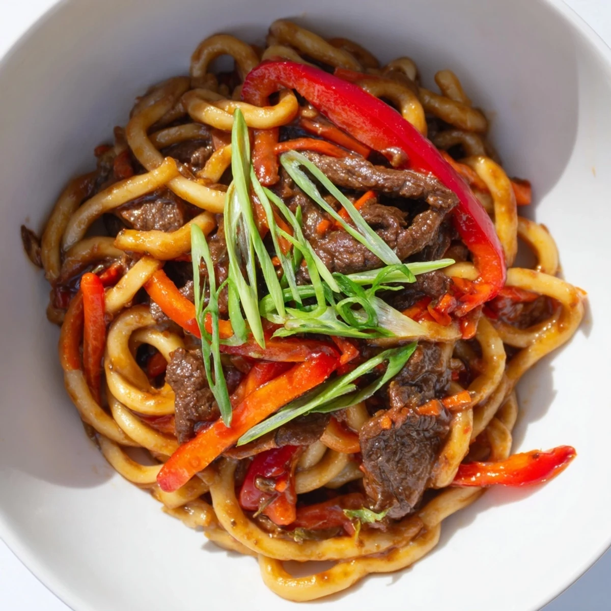 Vibrant Spicy Beef Stir Fry with Udon Noodles steams from a colorful wok, featuring tender beef and crisp vegetables.