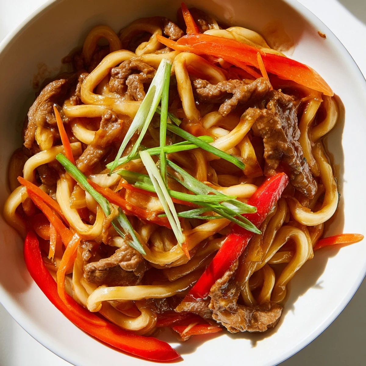 Close-up view of Spicy Beef Stir Fry with Udon Noodles highlighting the glossy sauce coating the noodles and beef.