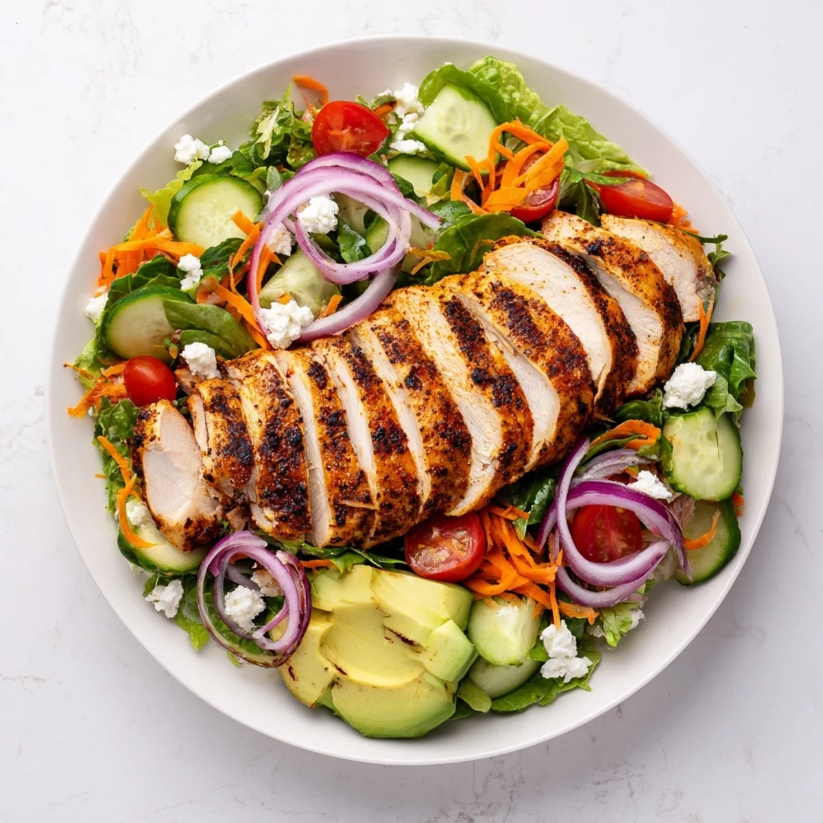 Freshly grilled chicken slices rest atop a crisp bed of mixed greens and cherry tomatoes in this Chicken Meal Prep Salad.