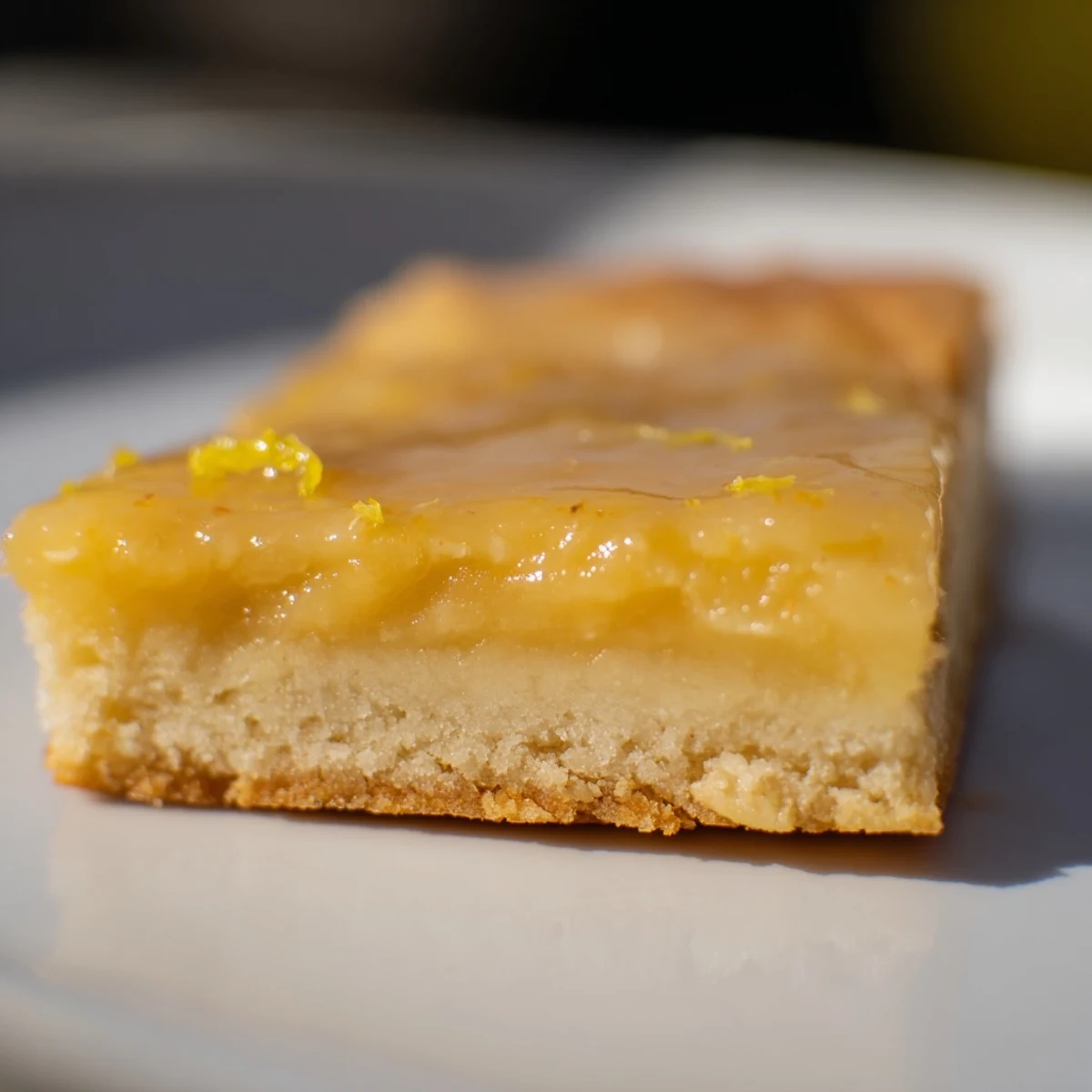 Freshly baked Lemon Dessert Bars with a golden shortbread crust and a vibrant, zesty lemon glaze on a wooden board.