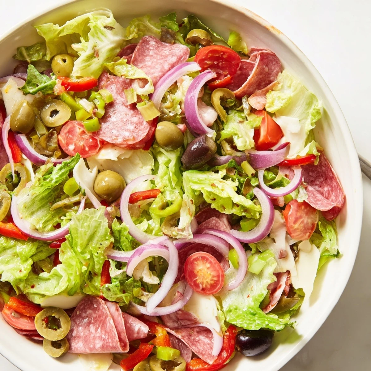 Hearty New Orleans Muffuletta Salad with colorful vegetables, salami, mortadella, and a robust olive vinaigrette.