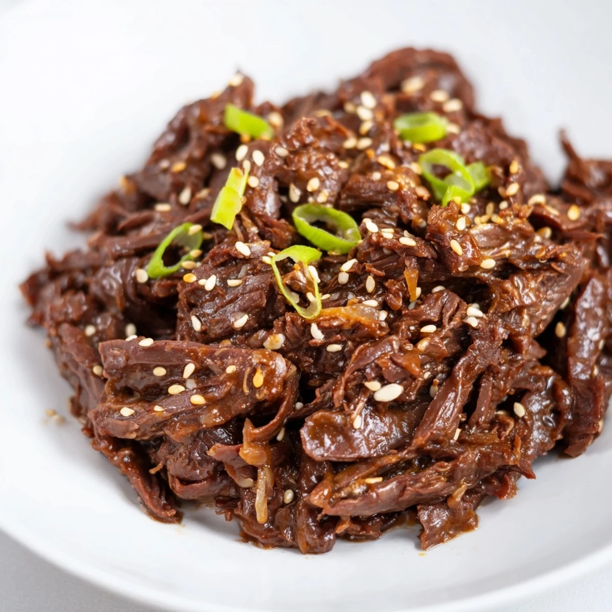 Tender Slow Cooker Korean Beef served over fluffy rice with sesame seeds and green onions