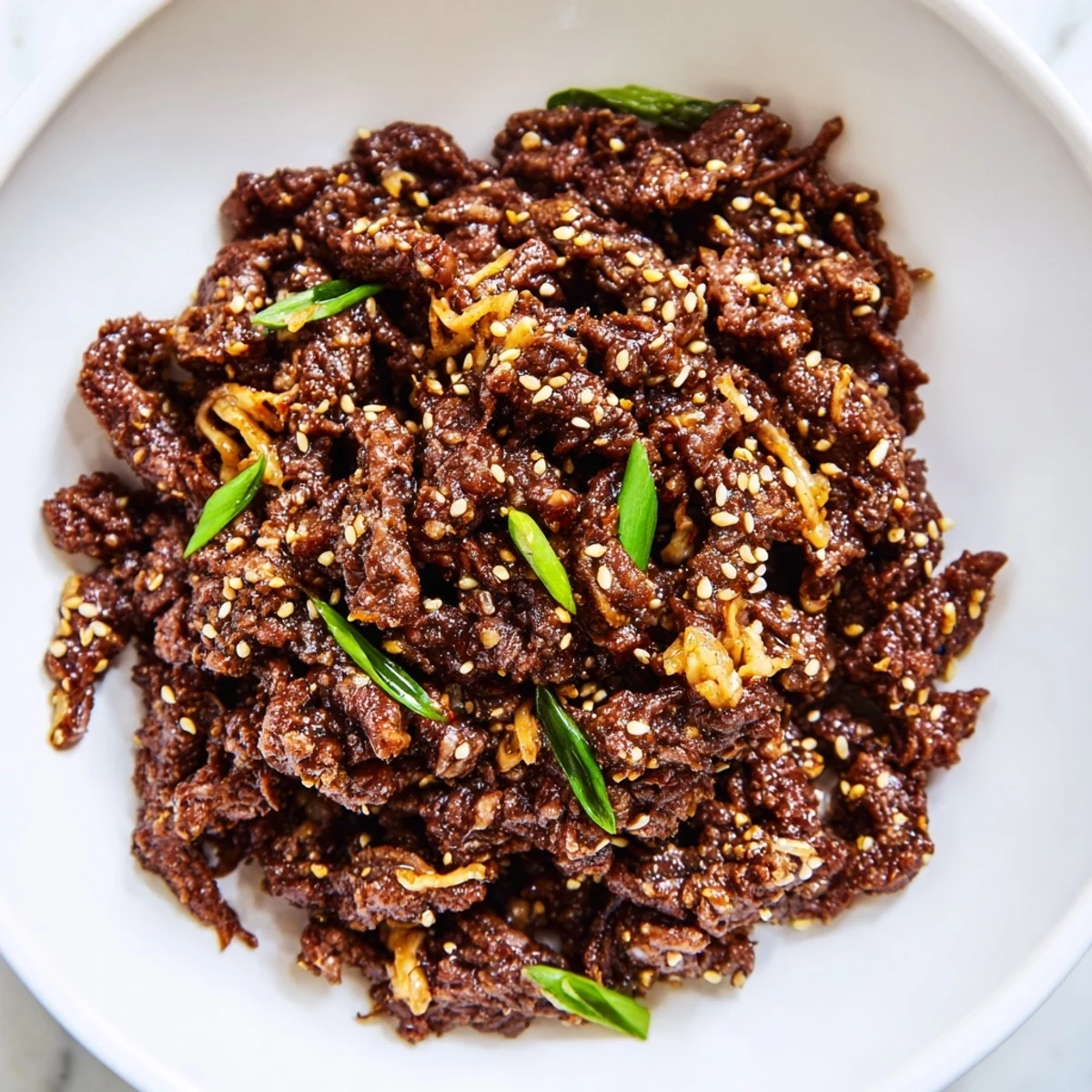 Slow Cooker Korean Beef shredded in a savory sauce, garnished with green onions and sesame seeds