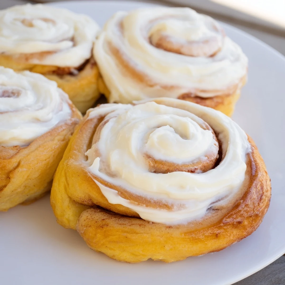 Freshly baked keto cinnamon buns cooling on a wire rack with creamy icing drizzled over the golden tops.