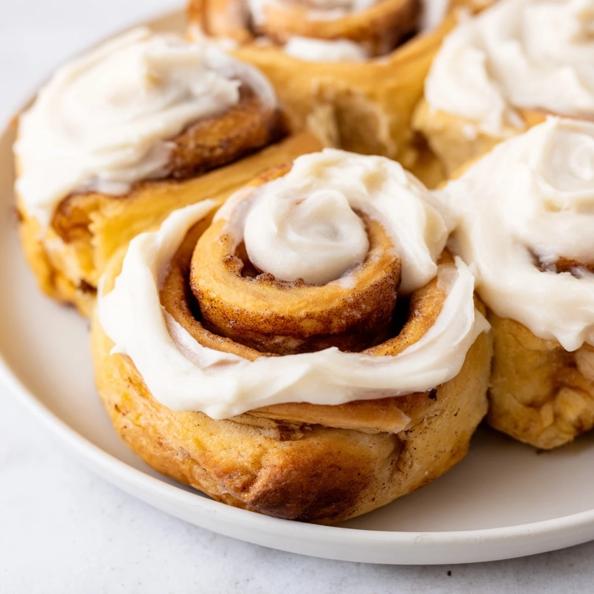 Warm keto cinnamon buns arranged in a round baking pan with a delicious sugar-free glaze and fluffy texture.