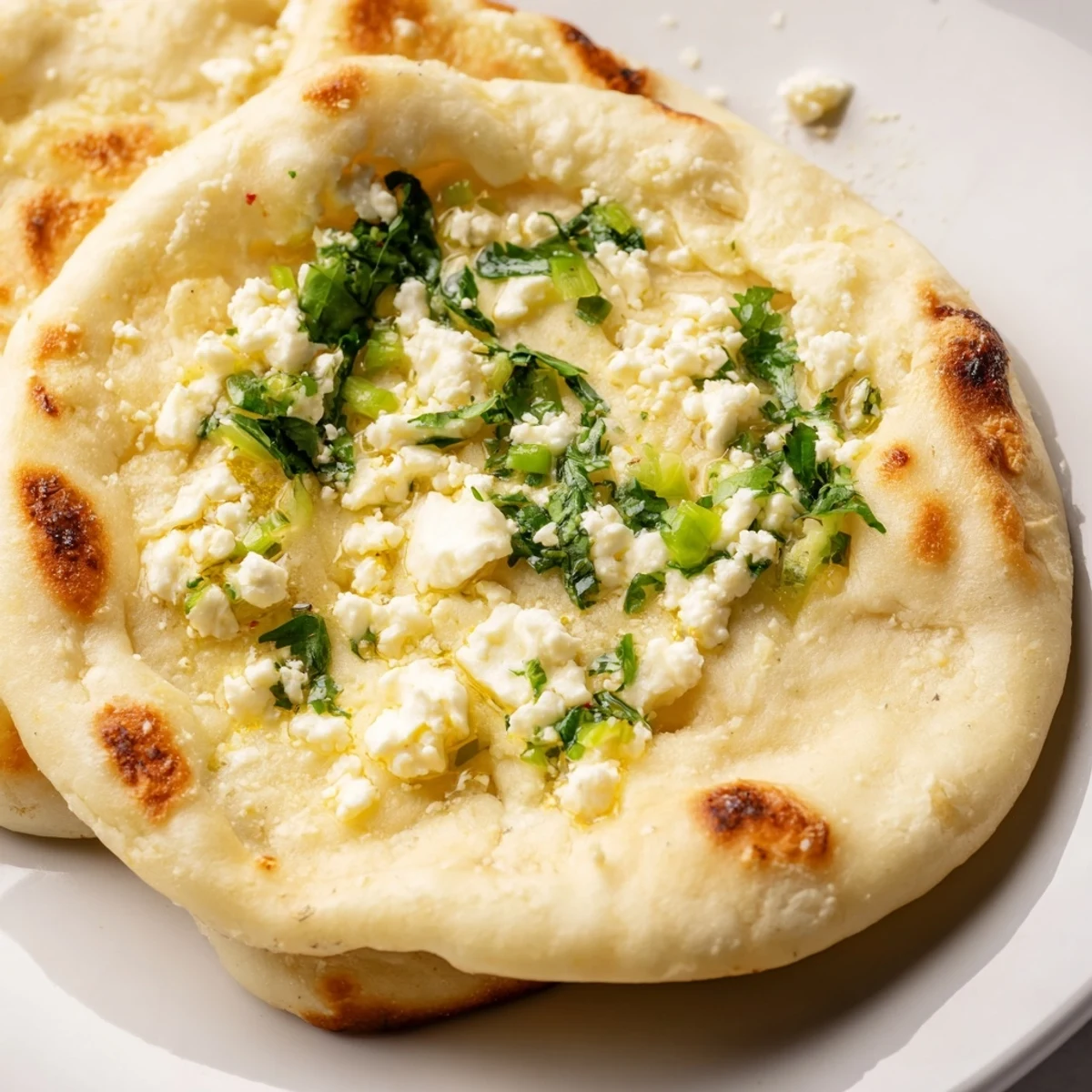 A warm, freshly cooked Cottage Cheese Garlic Naan brushed with garlic butter and chopped cilantro.