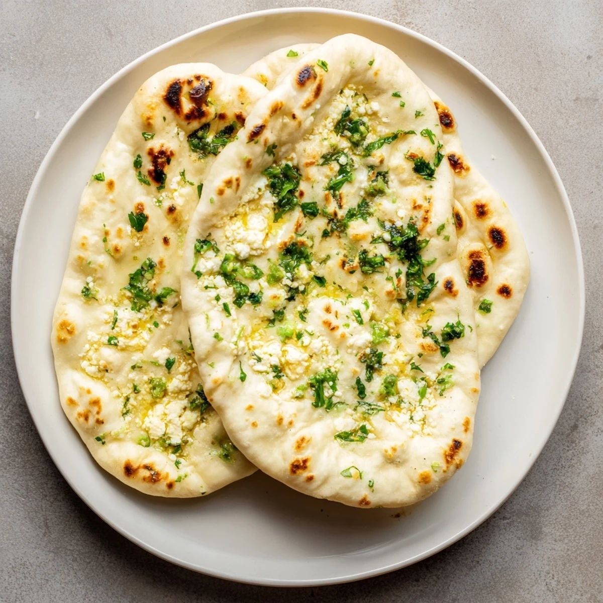 Golden-baked Cottage Cheese Garlic Naan served beside a bowl of spicy curry and fresh cilantro garnish.