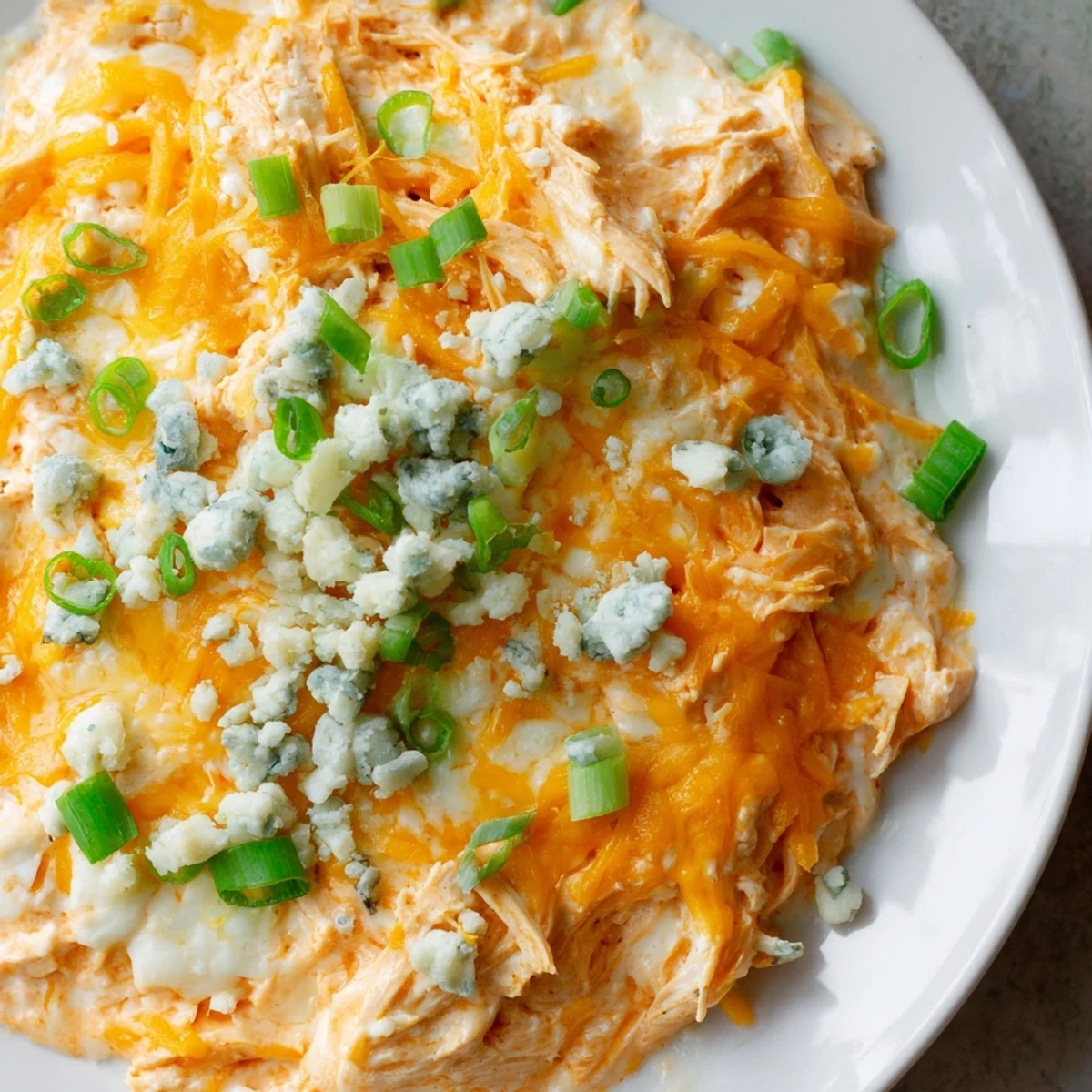 A serving spoon dips into Keto Buffalo Chicken Dip, revealing the cheesy, tender chicken inside a warm, oven-baked appetizer dish.
