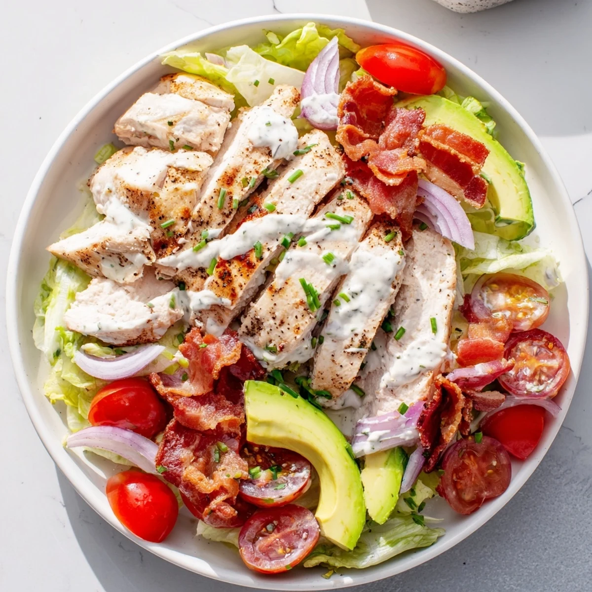 Freshly tossed BLT Chicken Salad with juicy chicken, crunchy bacon, ripe tomatoes, and creamy avocado on a bed of crisp romaine.