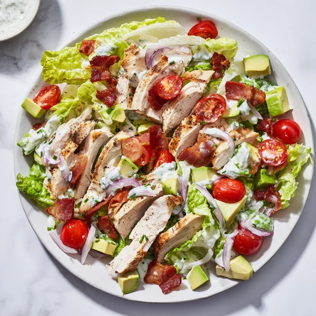 Colorful BLT Chicken Salad bowl garnished with fresh chives, served with a crisp white wine for an easy gluten-free main dish.