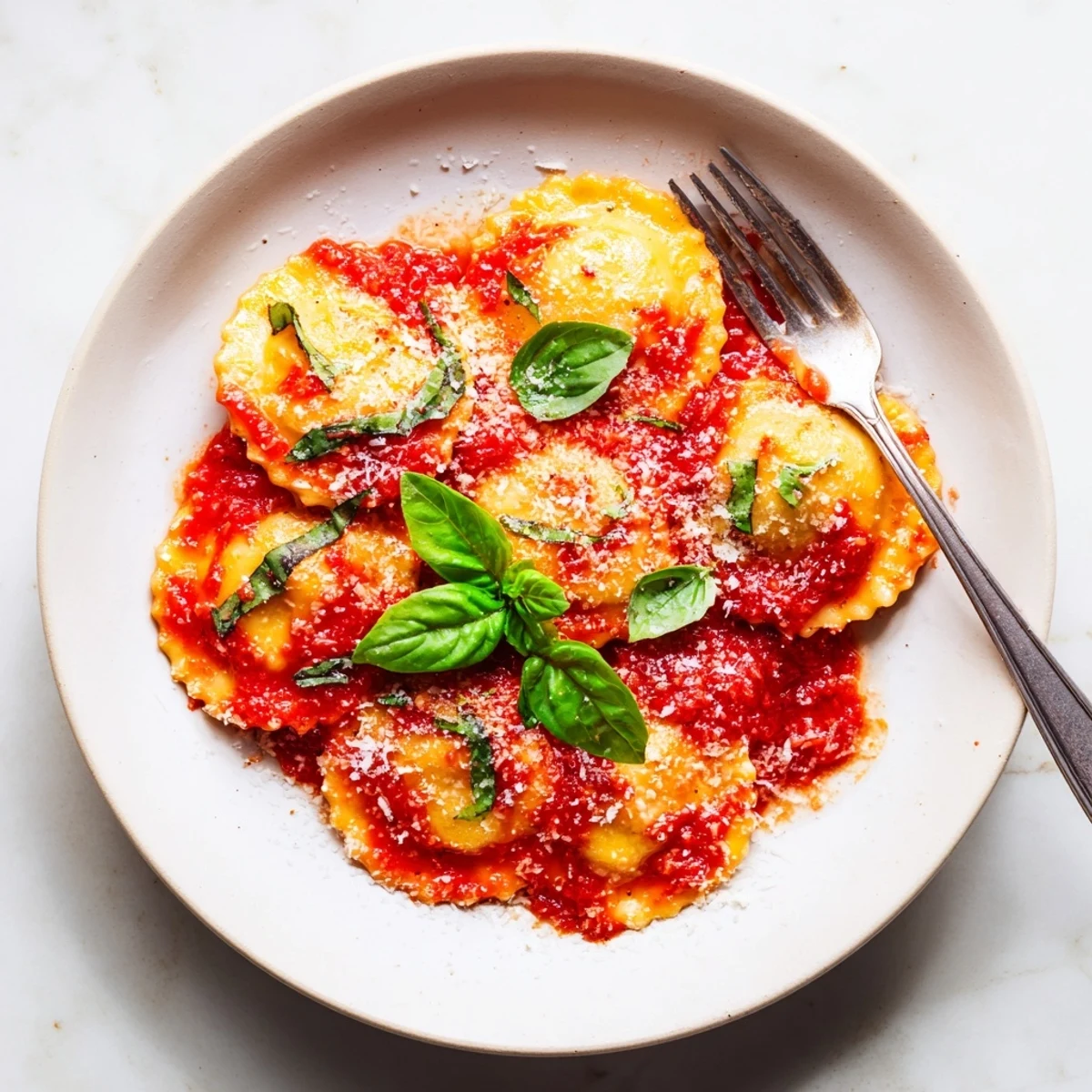 Close-up of cheesy ravioli coated in a rich tomato sauce, finished with fresh basil leaves for a flavorful meal.