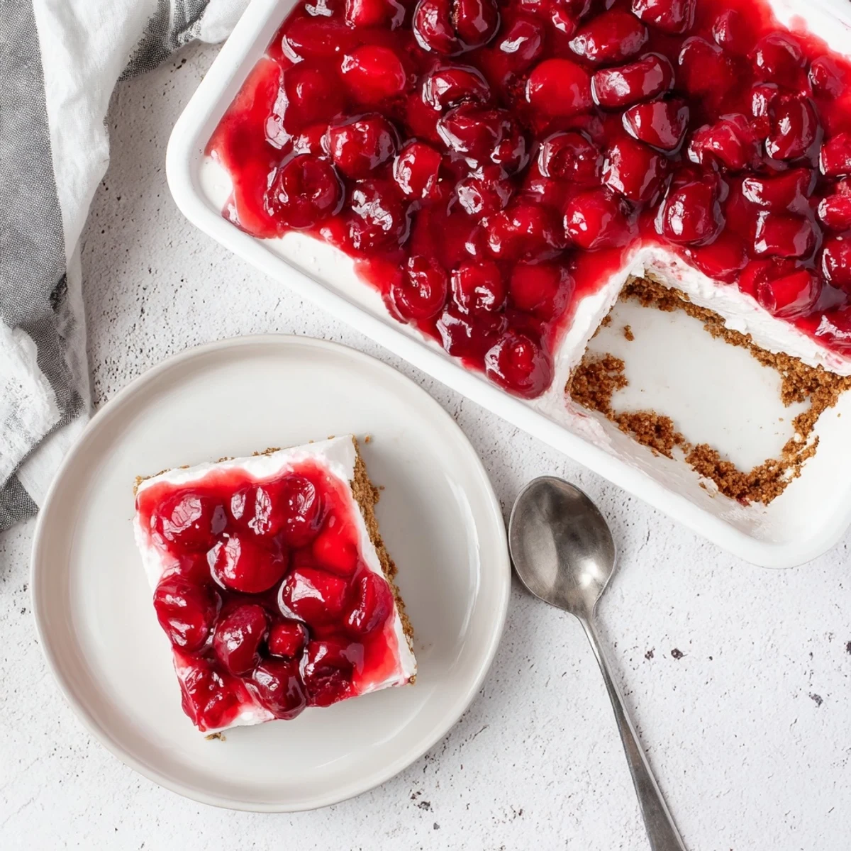 A slice of Classic Cherry Delight with red cherries on creamy layer and a graham cracker crust.