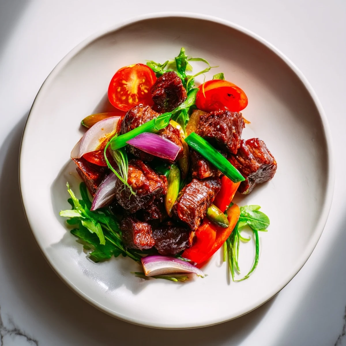 Cubes of seared beef sit atop crisp watercress and tomatoes in this Vietnamese Shaking Beef dish, with lime sauce on the side.