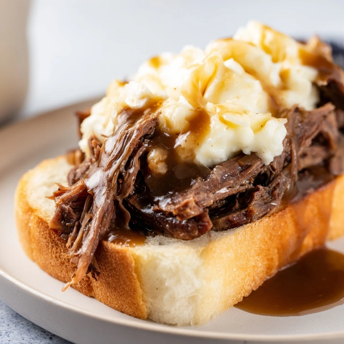 A hearty plate of Slow Cooker Beef Manhattan with tender beef, smooth potatoes, and savory gravy ready for a cozy dinner.