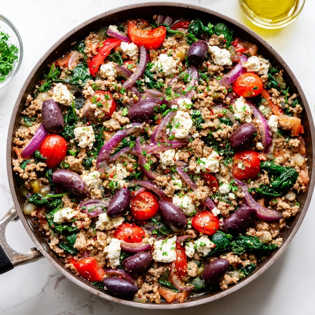 A close-up of Mediterranean Keto Skillet with Ground Chicken, Olives & Feta featuring juicy browned meat and bright red cherry tomatoes.