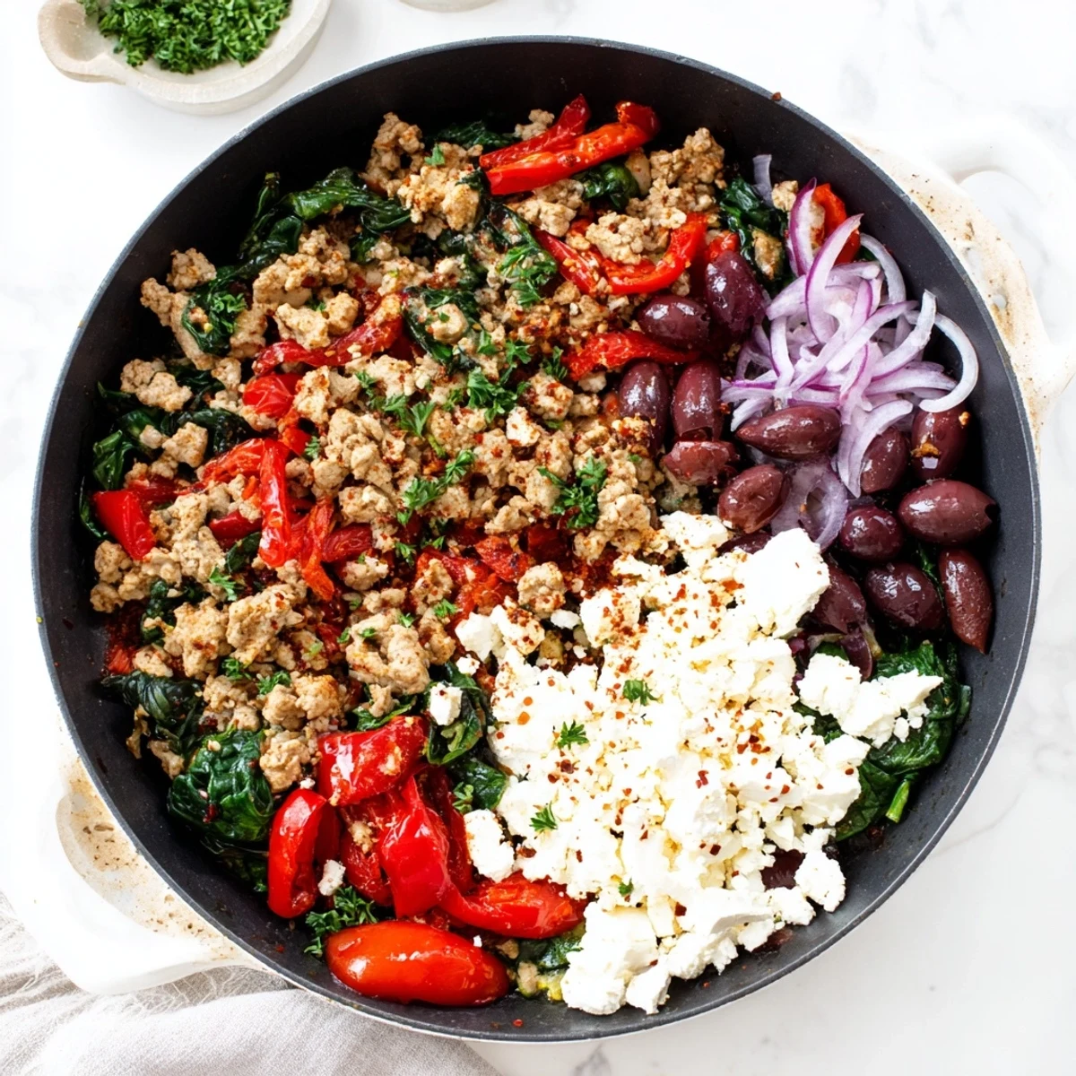 Vibrant Mediterranean Keto Skillet with Ground Chicken, Olives & Feta served in a rustic iron pan on a linen tablecloth.