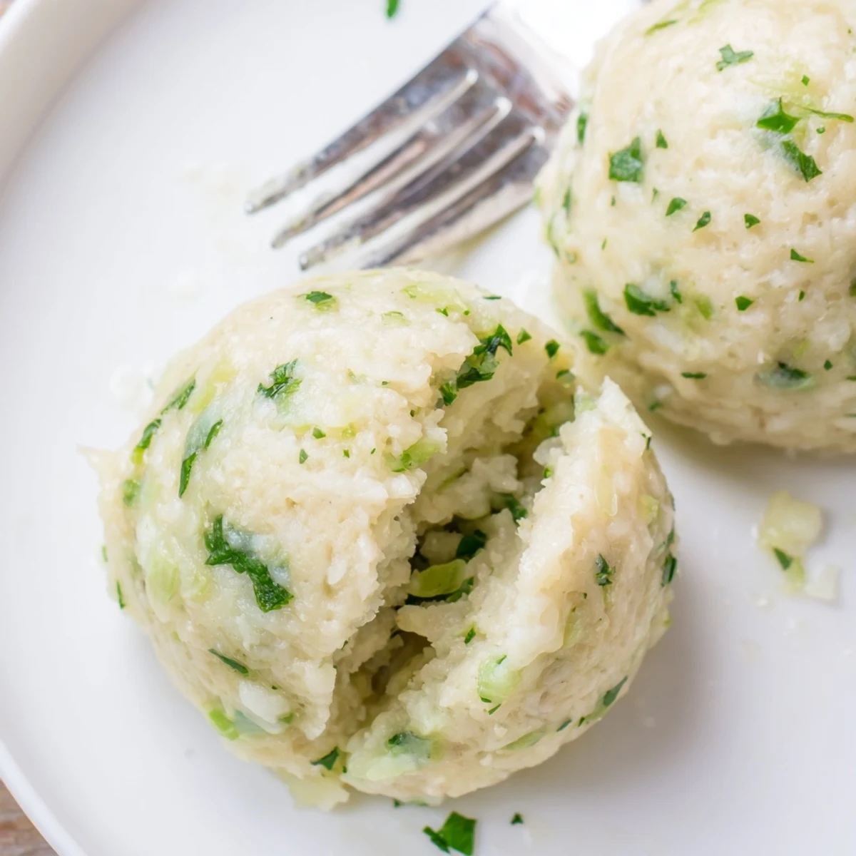 A bowl of German Cabbage Dumplings simmered in broth, accompanied by creamy mushroom sauce for dipping.