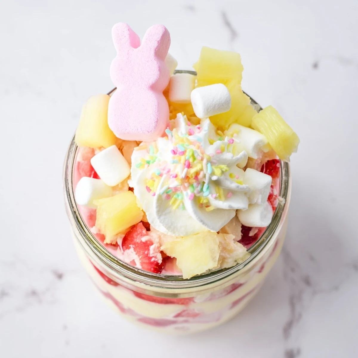 Festive Jello Pie Easter Bunny Parfait In A Jar on a pastel plate highlights marshmallow bunny candies and juicy diced fruit.