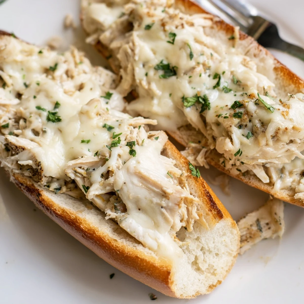 A close-up of Viral Chicken Alfredo Garlic Bread showing creamy Alfredo sauce and toasted crust.
