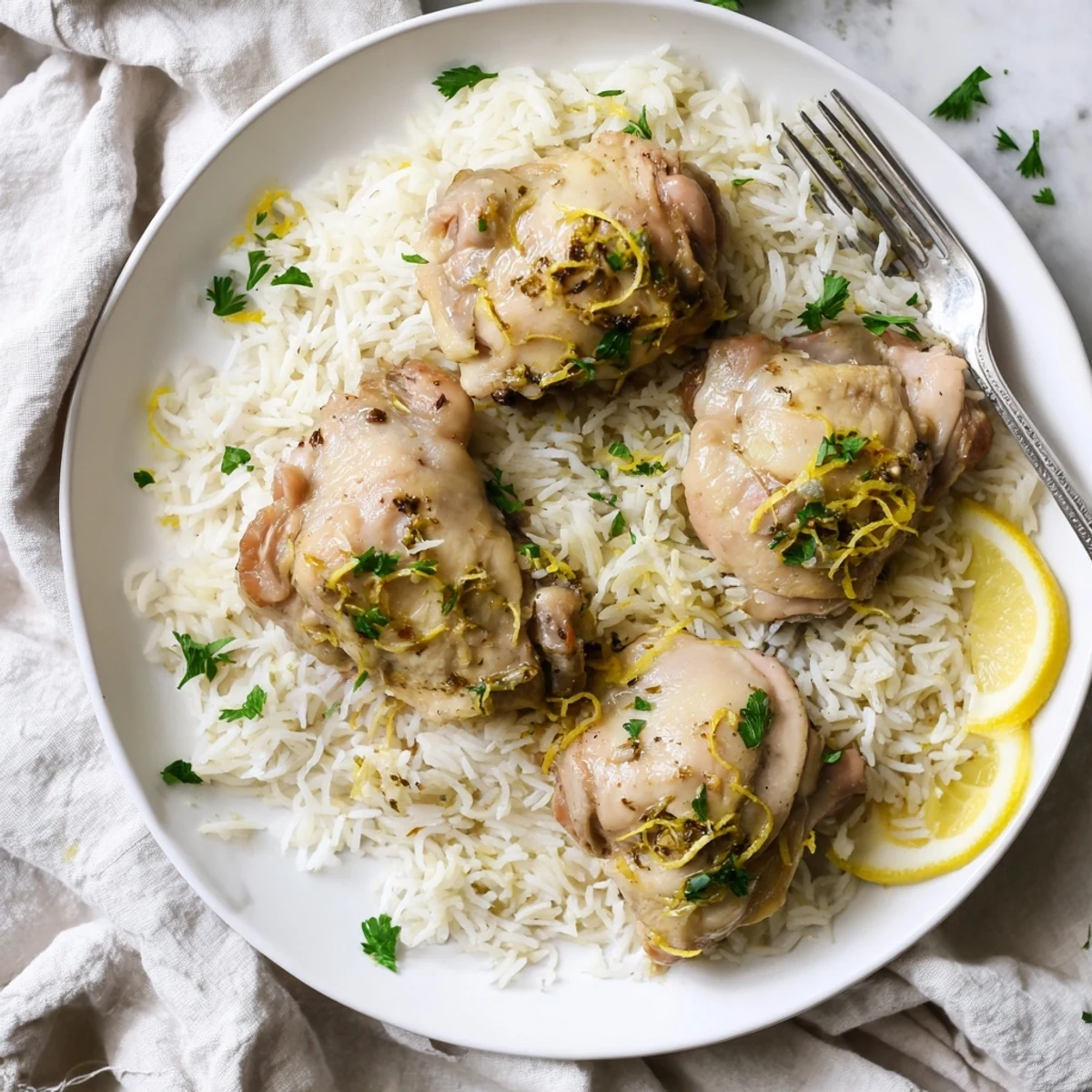 Slow Cooker Lemon Herb Chicken With Fluffy Rice plated with lemon wedges and steaming juices for serving.