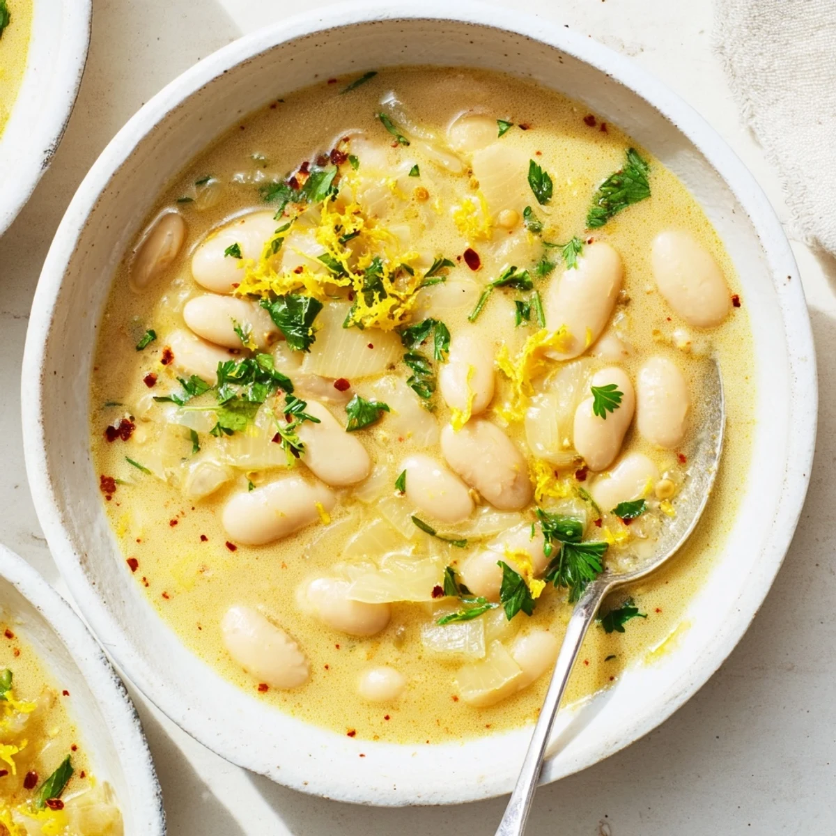 Close-up of Miso Butter Brothy Beans showcasing rich broth, sautéed onions, and melted butter for a savory finish.