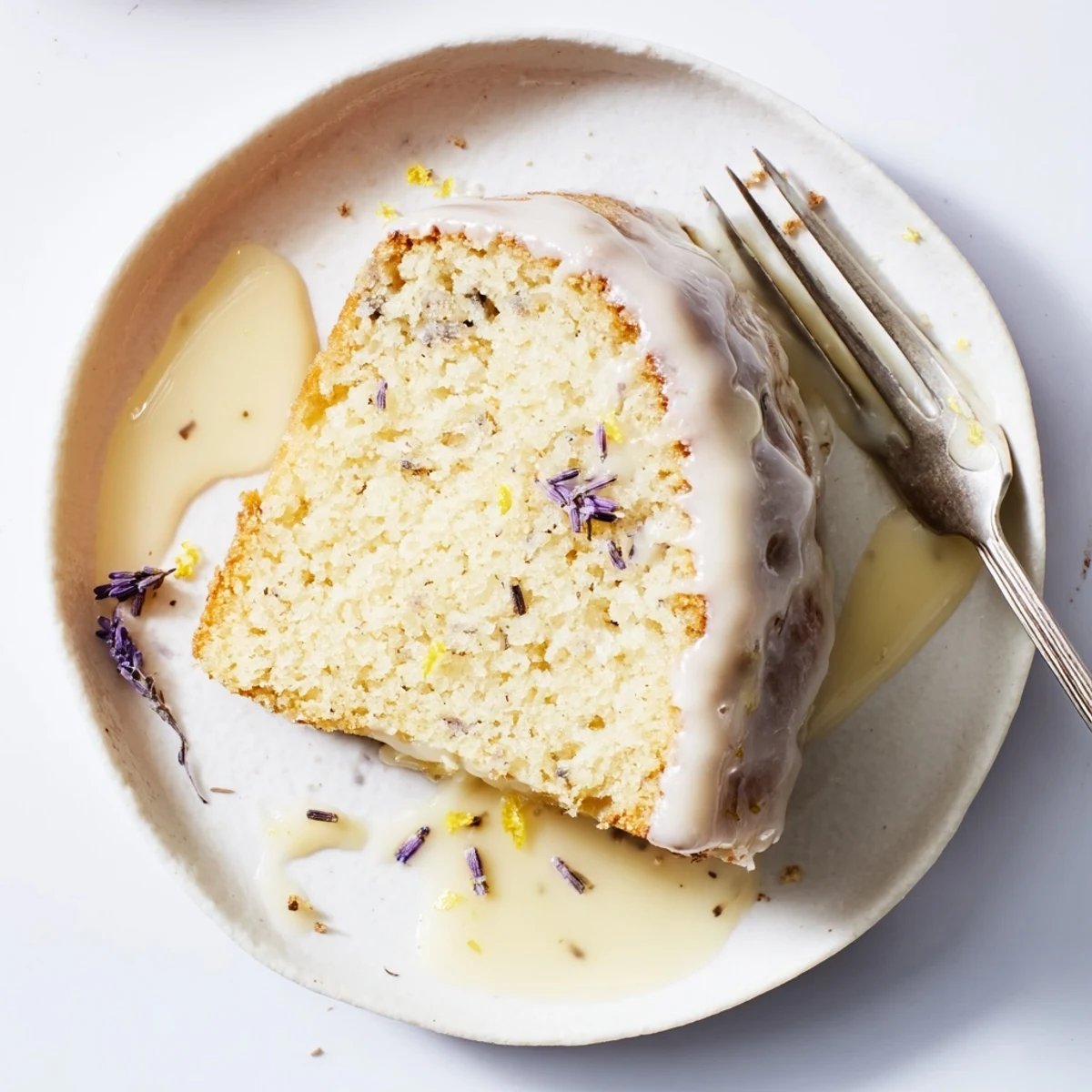 Golden lemon lavender cake drizzled with white glaze and topped with purple lavender buds