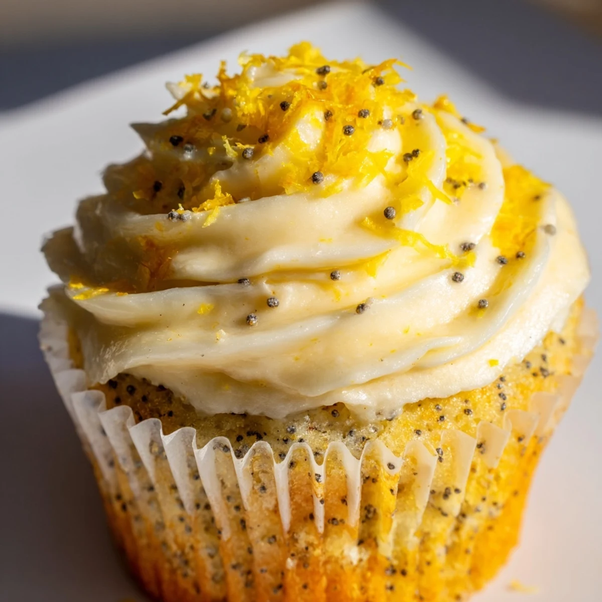 Golden lemon poppy seed cupcakes topped with creamy white cream cheese frosting and sprinkled with fresh lemon zest