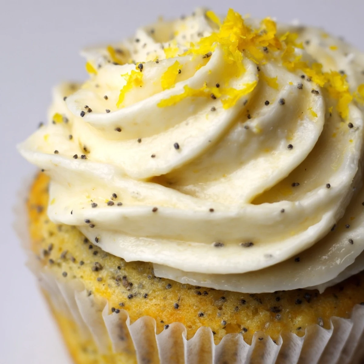 Batch of freshly baked lemon poppy seed cupcakes cooling on wire rack with fluffy lemon cream cheese frosting