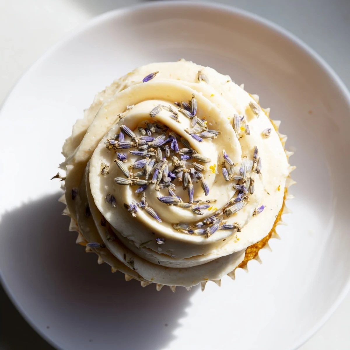 Two spring lemon lavender cupcakes with swirled buttercream frosting and edible flower garnish