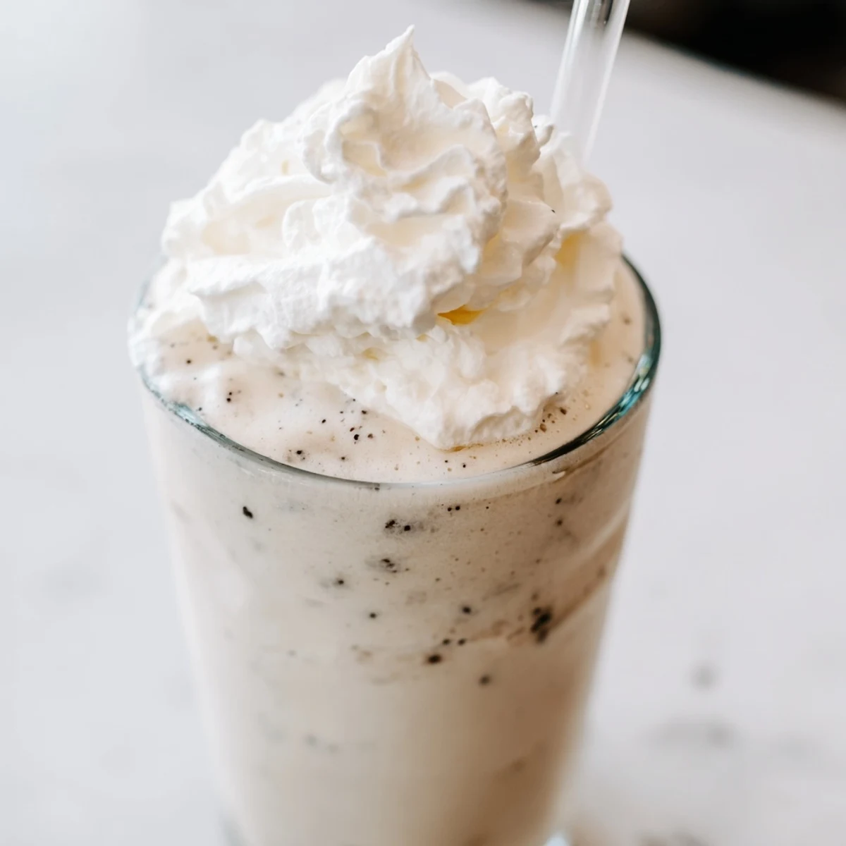 Homemade vanilla bean frappuccino with sweet whipped cream garnish served with straw