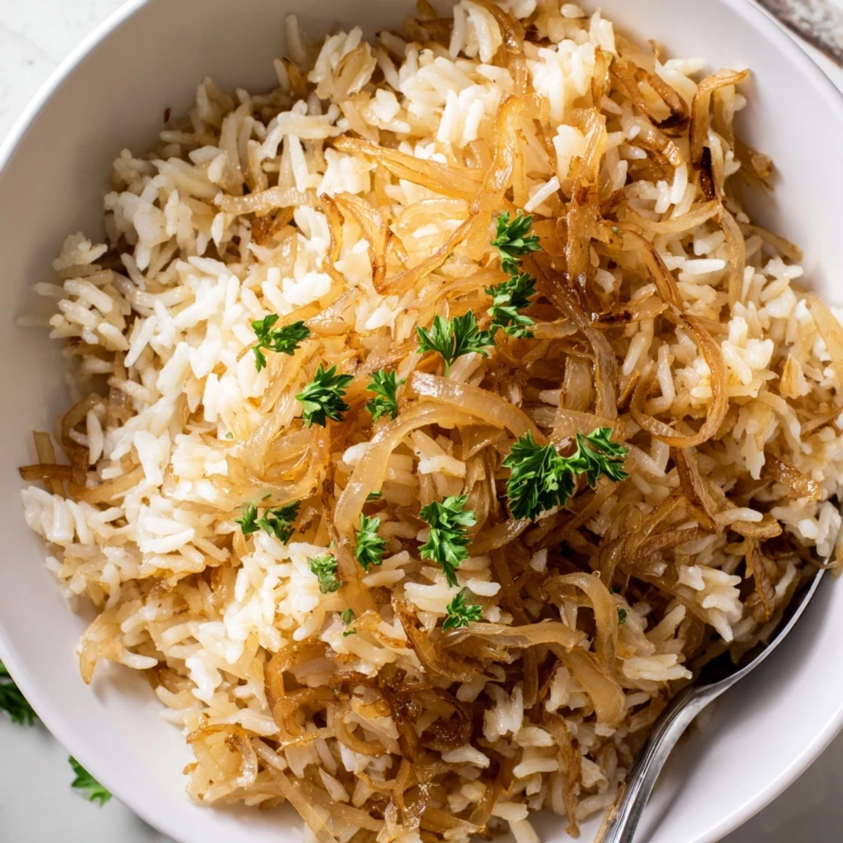 Golden French onion butter rice sprinkled with fresh parsley and grated Gruyère cheese in a white serving bowl