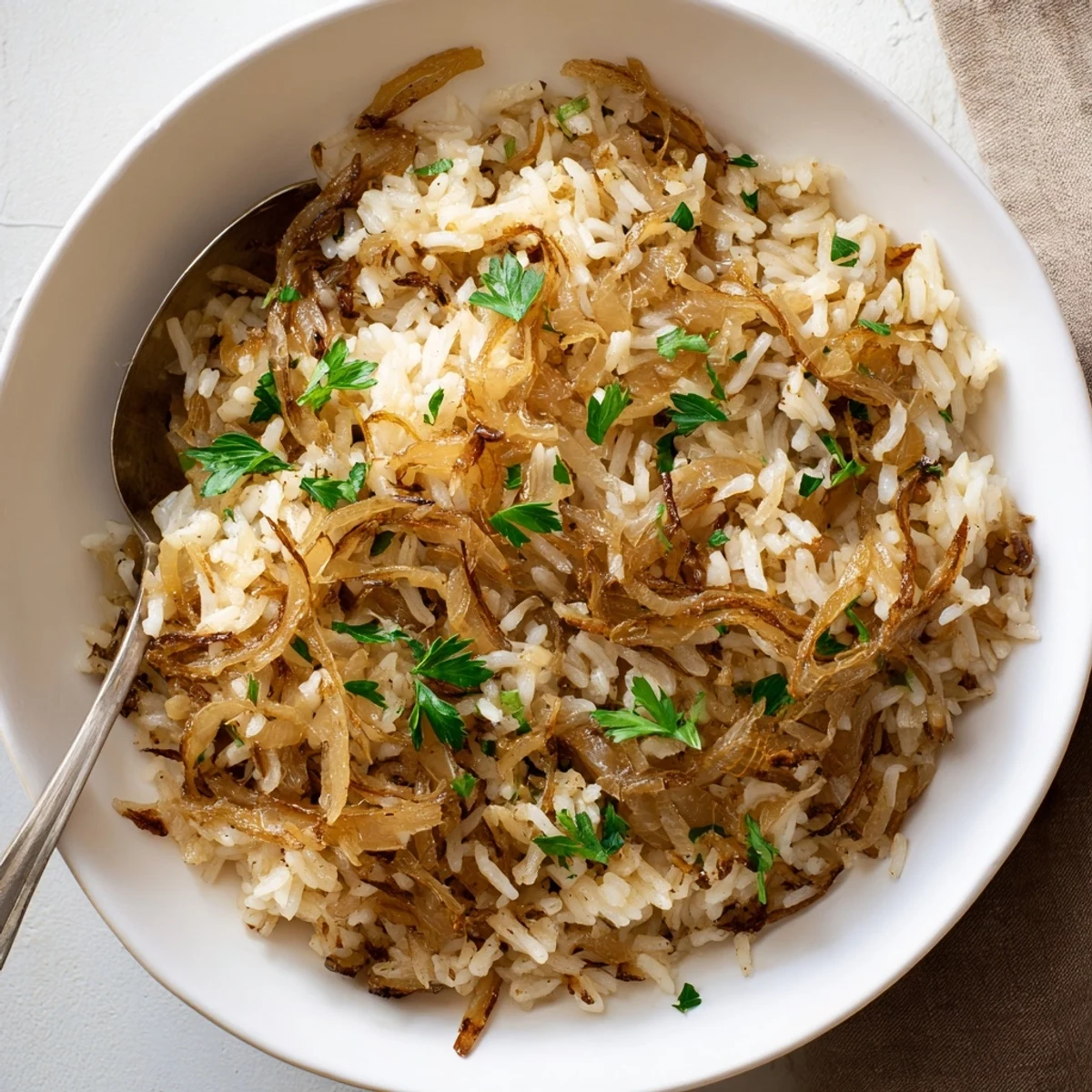 Fluffy white rice dish with caramelized golden onions and melted butter glistening under soft kitchen lighting