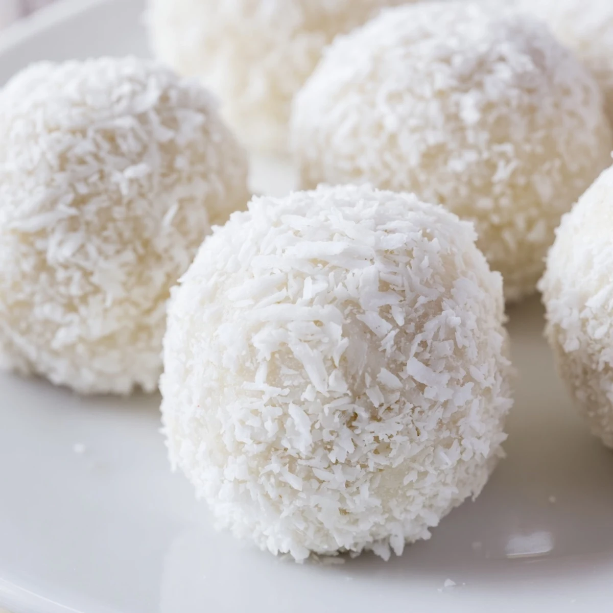 White coconut bunny tails rolled in powdered sugar arranged on a festive Easter serving platter